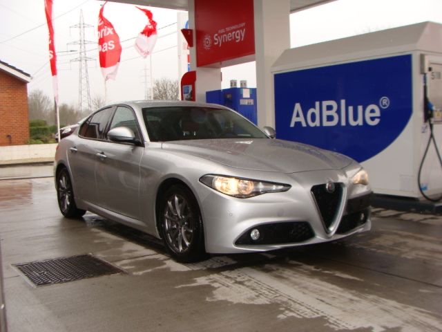 Une Alfa Romeo Giulia grise à la pompe AdBlue de la station