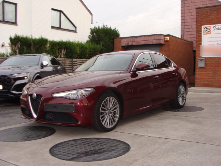 Une Alfa Romeo Giulia rouge devant le garage