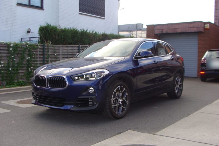 Un BMW X2 bleu foncé devant le garage