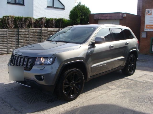 Un Jeep Grand Cherokee gris devant le garage