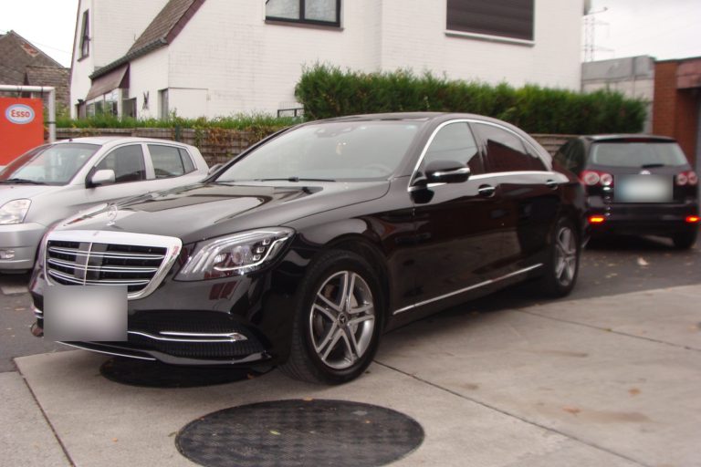 Une Mercedes-Benz Classe S noire devant le garage