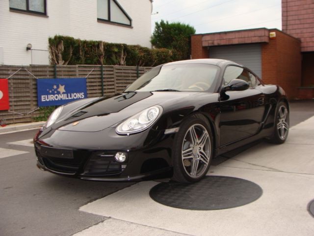 Une Porsche Cayman noire devant le garage
