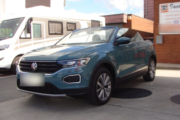 Un Volkswagen T-Roc cabriolet bleu-vert devant le garage