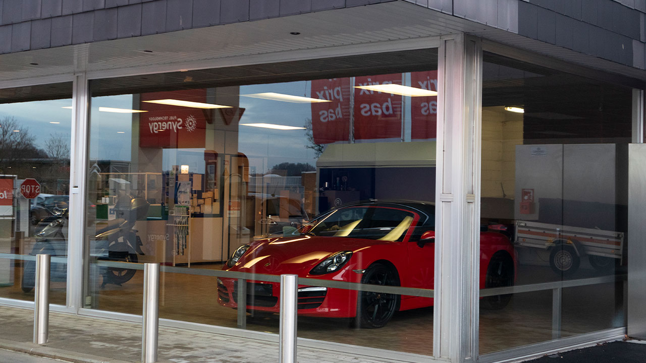 Une Porsche rouge exposée dans la vitrine du shop de la station